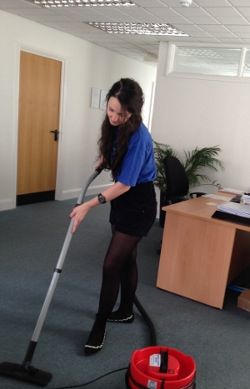 female vacuuming carpet in office